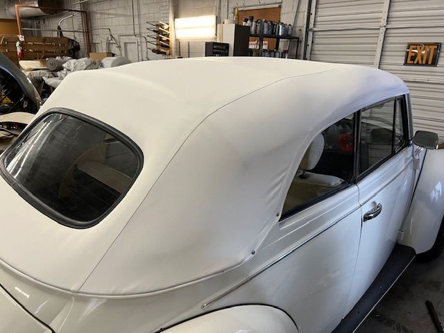 White convertible car with a white top in a garage setting.