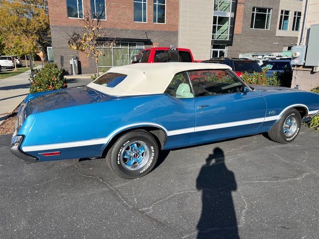 Blue convertible car with white top and stripe parked outside a building.