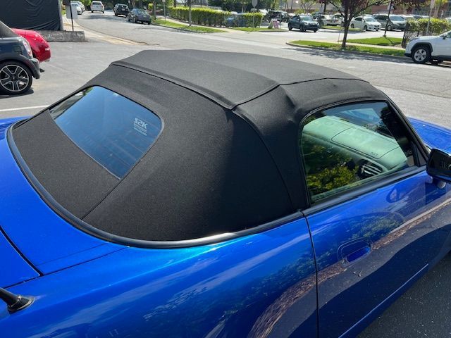Blue convertible car with black soft top, parked outdoors.