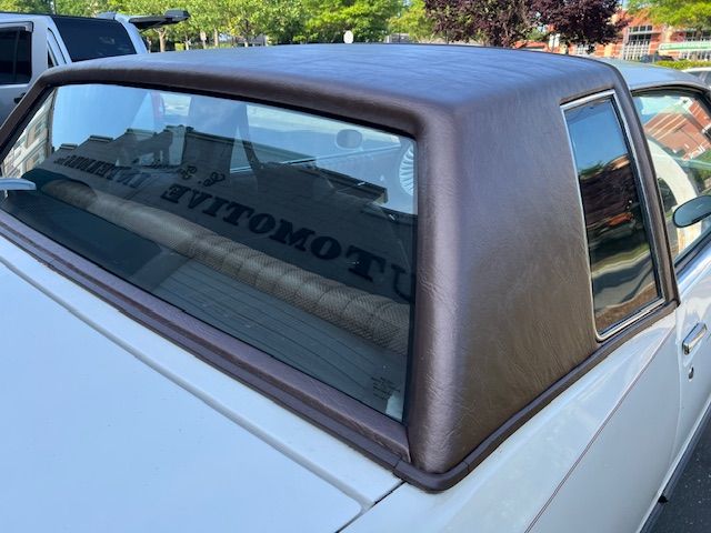 Brown vinyl roof on a white vintage car, angled view.