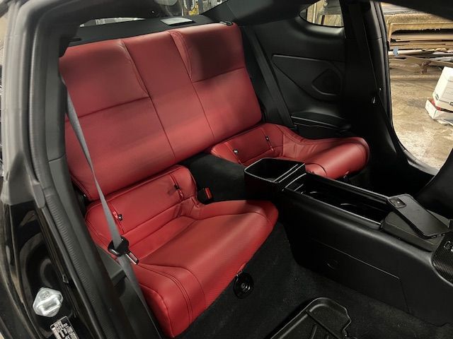 Red leather rear car seats in a black interior, with a center console.