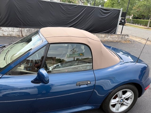 Blue convertible car with tan soft top; parked outside.
