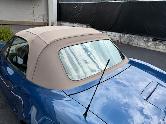 Blue convertible car with a tan soft top.