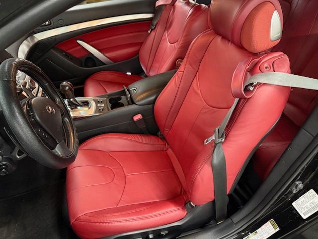 Red leather car seats in a black interior, with a seatbelt and steering wheel visible.