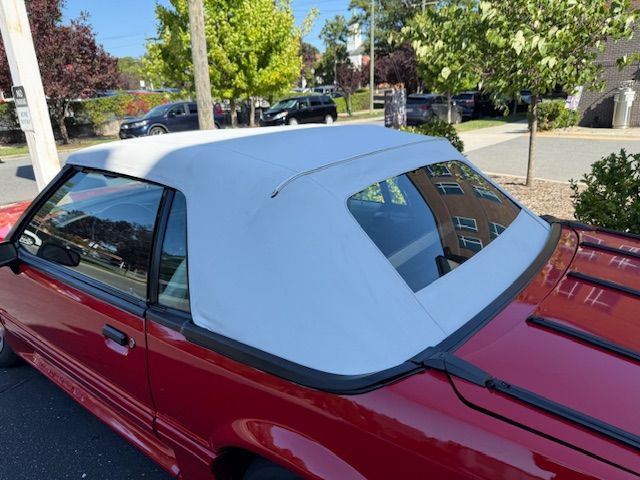 Red convertible car with a white top, parked outdoors on a sunny day.
