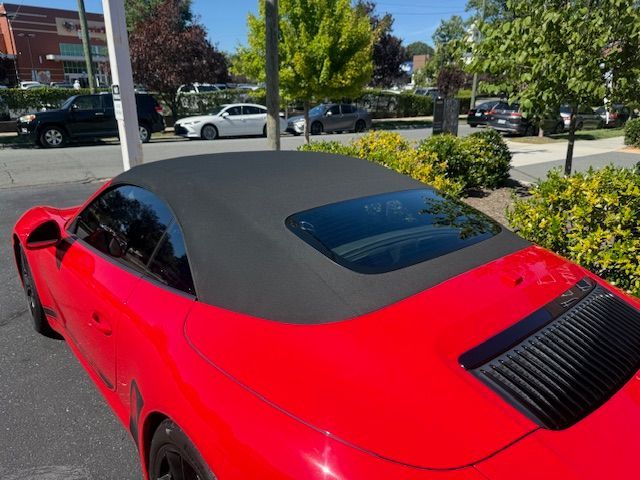 Red Porsche convertible with black top parked outdoors.