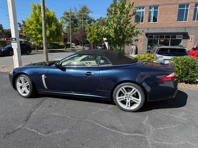 Blue Jaguar convertible parked outside a brick building on a sunny day.