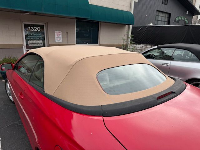 Red convertible car with tan soft top.