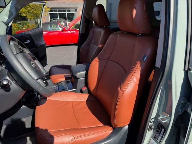 Interior of a car with brown leather seats and a black dashboard. A red car is visible outside.