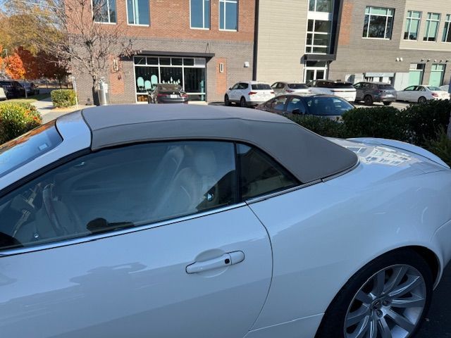 White convertible car with a tan soft top, parked outdoors.