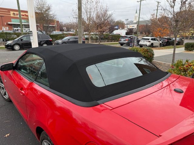 Red convertible car with a black top in a parking lot.