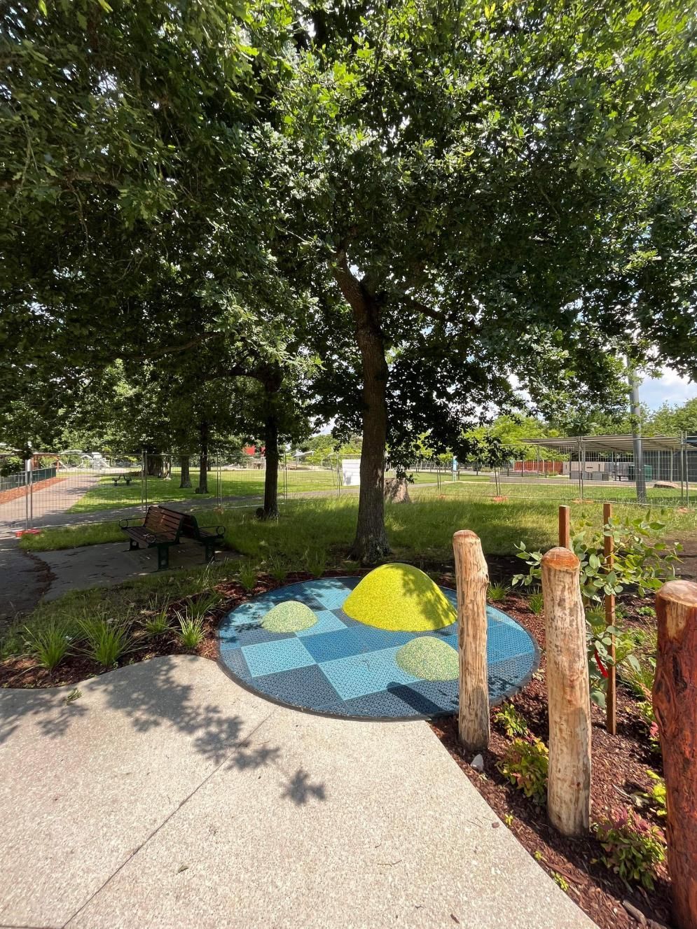 There is a playground in the middle of a park with a tree in the background.