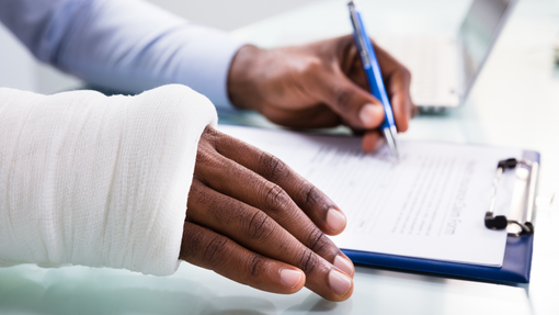 A person with a cast on their arm is writing on a clipboard.