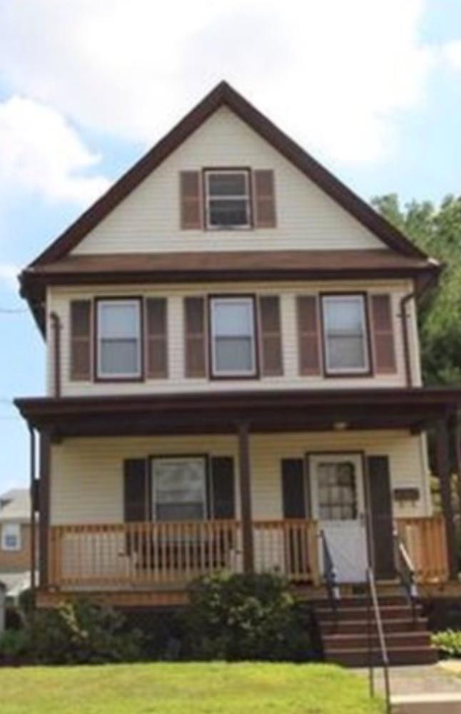 Front view of a two-story home with outdated siding and trim, ready for exterior renovation by DMF Construction in NJ