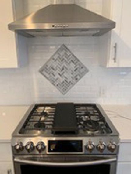 Modern kitchen with custom tile backsplash and stainless steel range hood by DMF Construction in Scotch Plains, NJ.