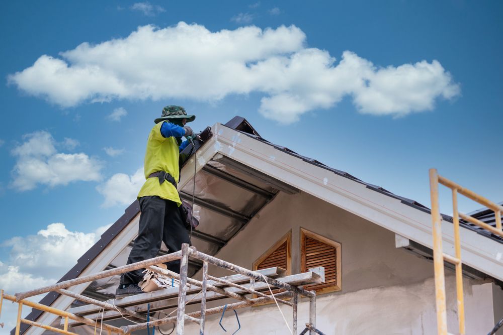 A man is working on the roof of a house on a scaffolding.