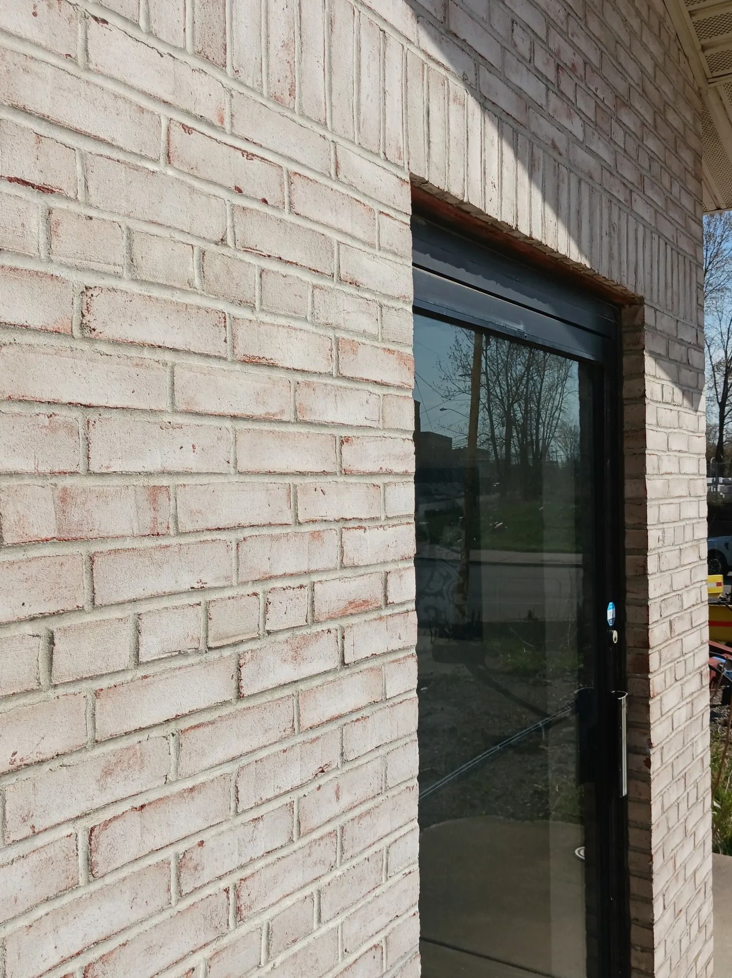 Light brick wall next to a sliding glass door with a black frame.