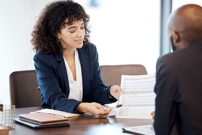 Awoman is sitting at a table talking to a man.