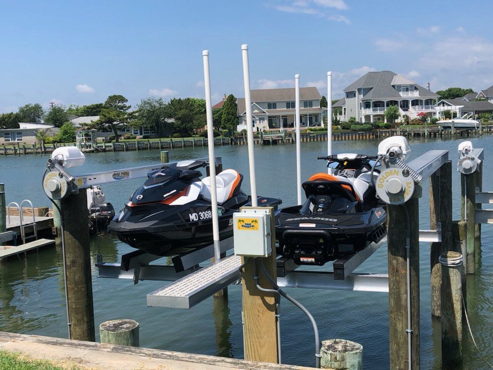 Two jet skis are docked at a dock in the water.