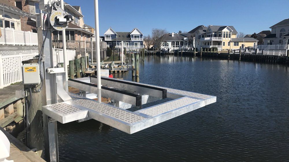 A boat lift is sitting on a dock next to a body of water.