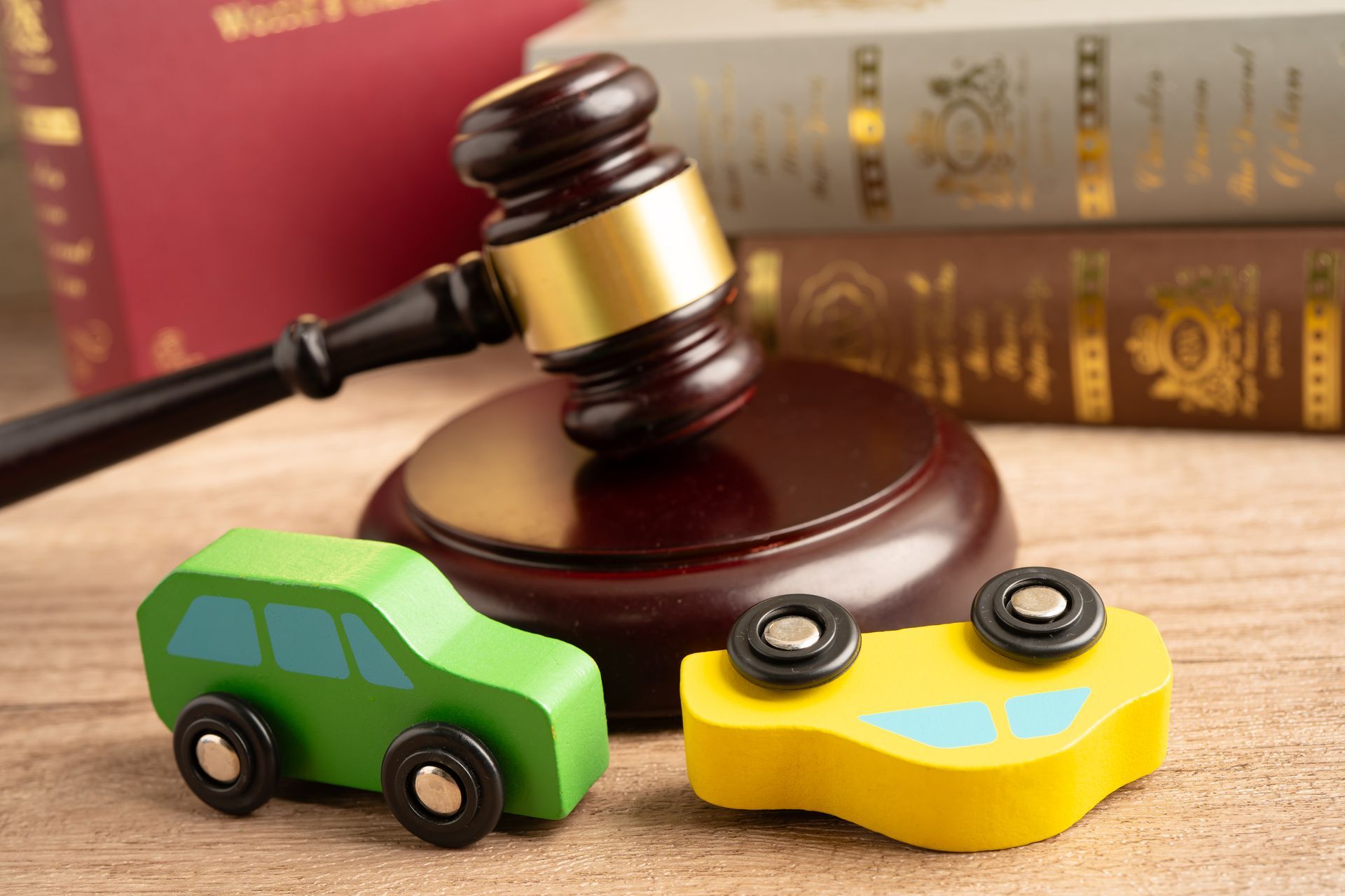 Judge’s gavel with toy cars and law books, symbolizing auto accident laws.