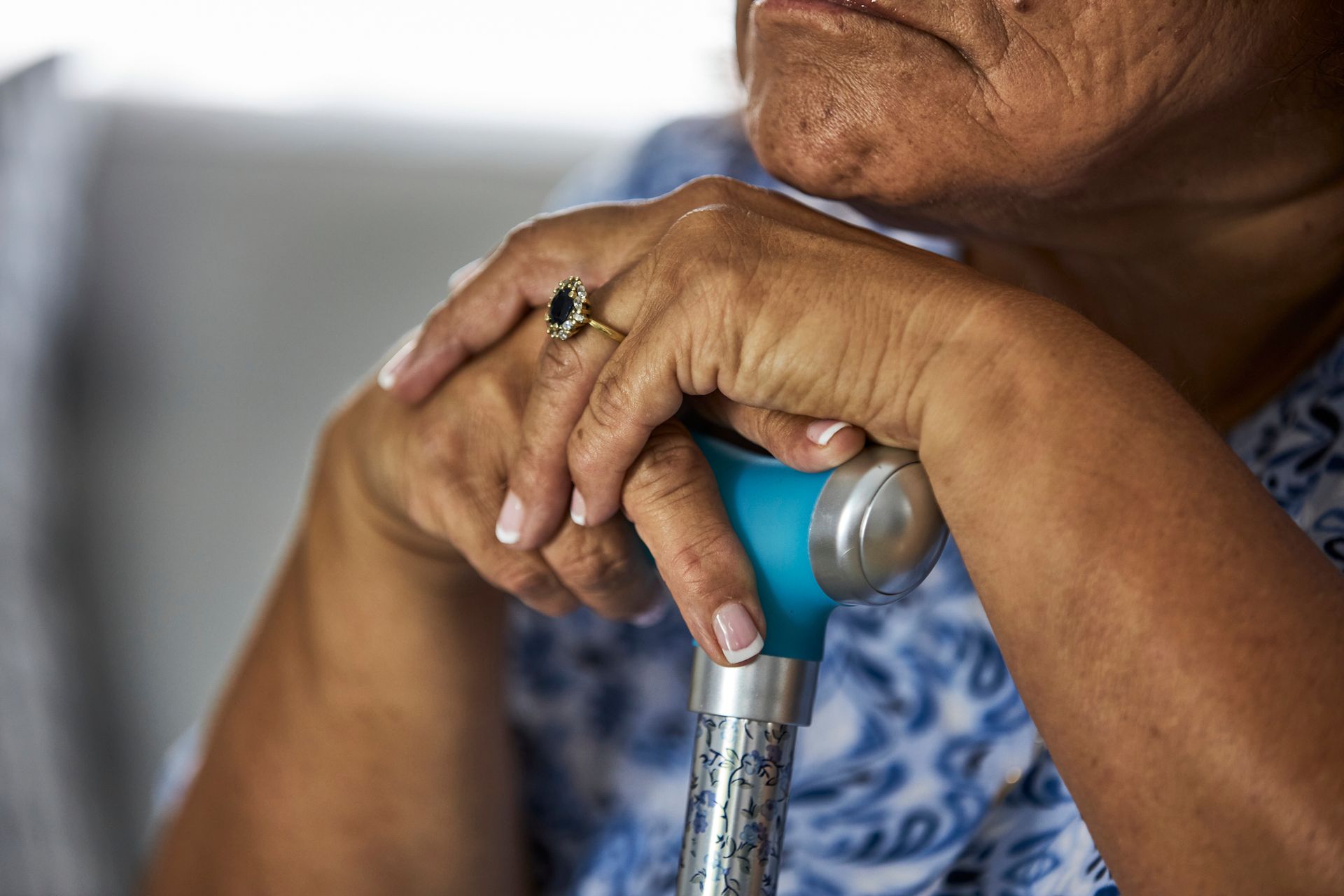 Elderly person resting hands on a cane with a ring on one finger. Elderly person resting hands on a cane with a ring on one finger.