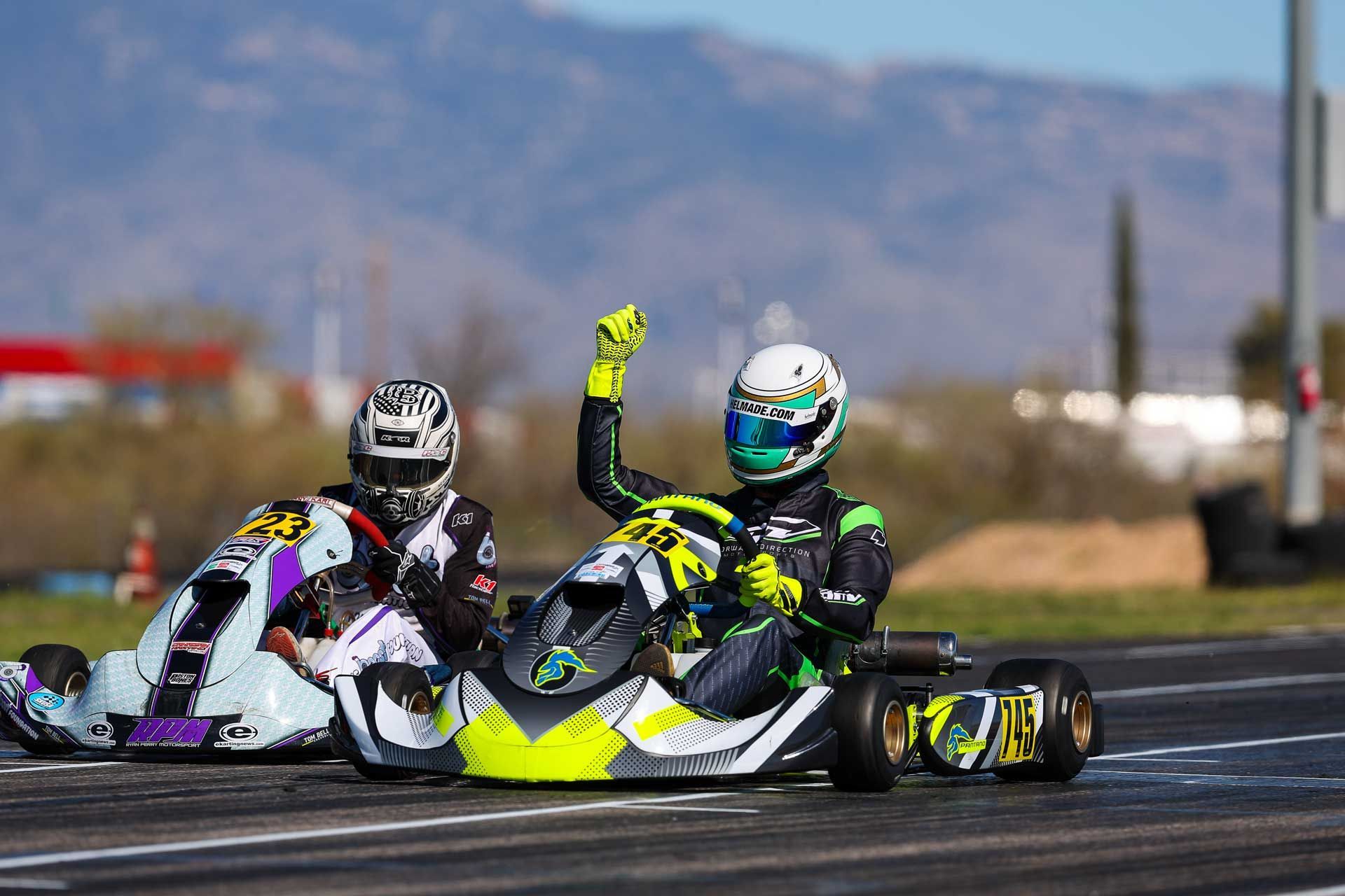 Two people are racing go karts on a track.