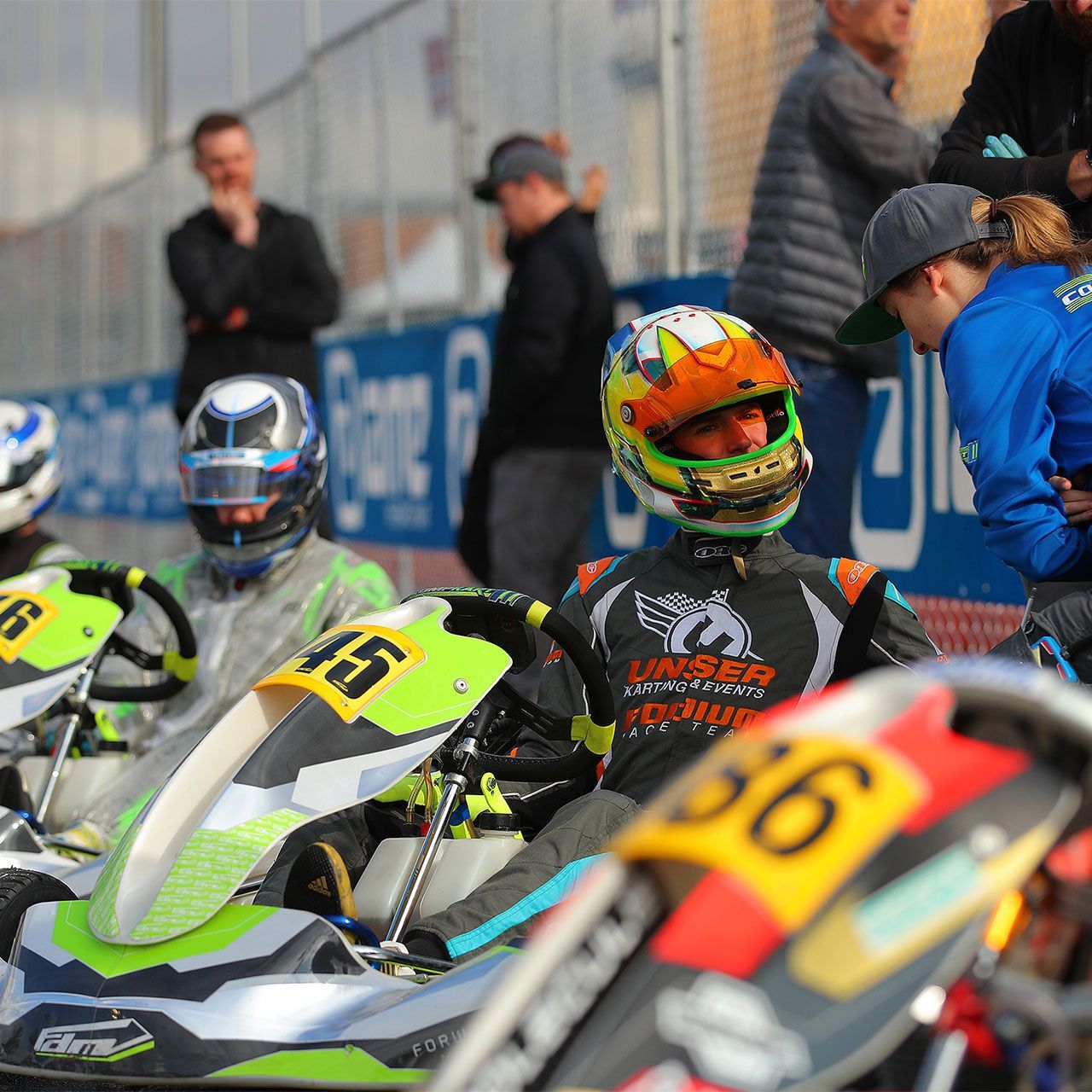 A man wearing a helmet sits on a go kart with the number 36 on it