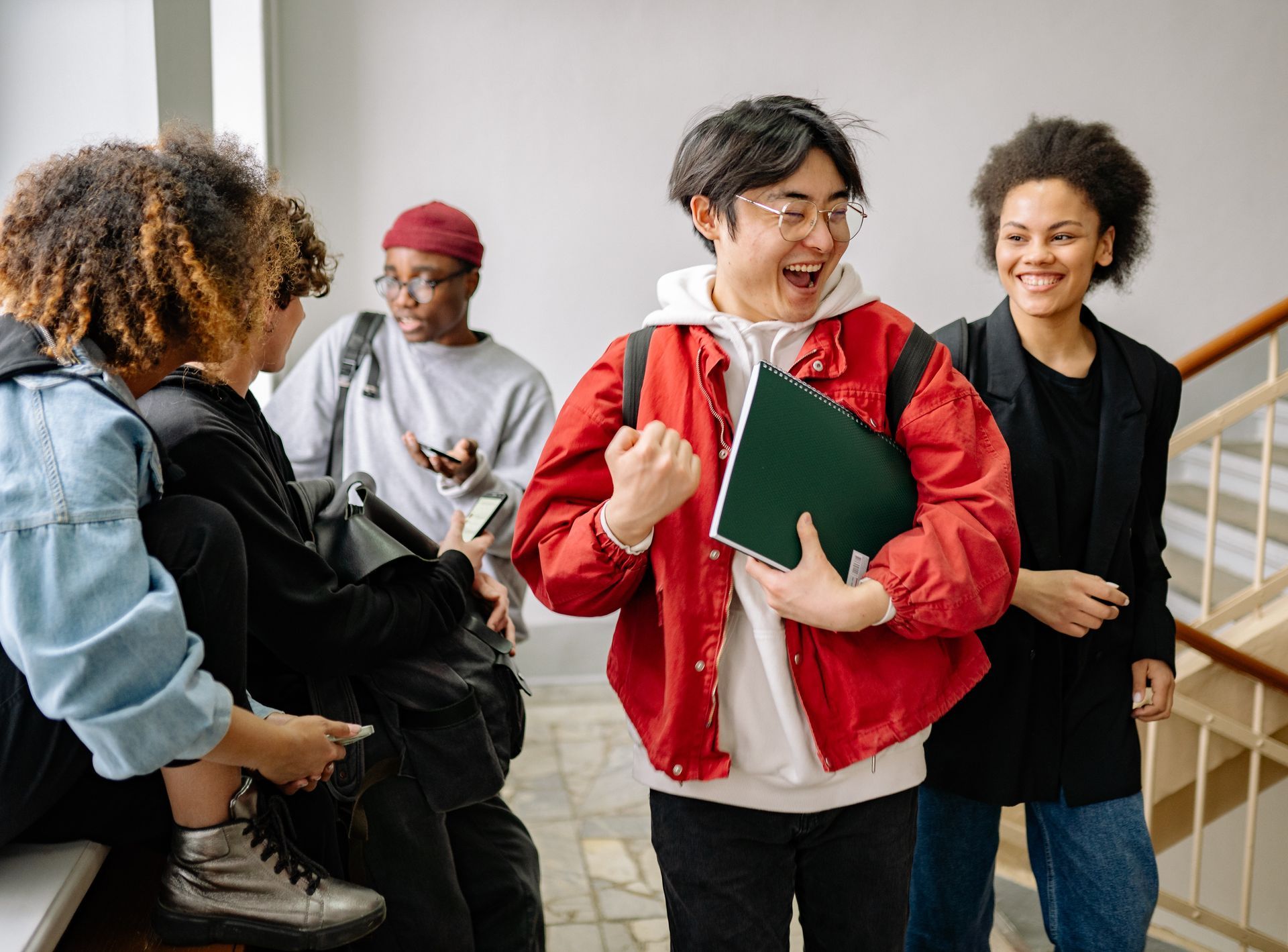 A group of young people are standing in a hallway talking to each other.