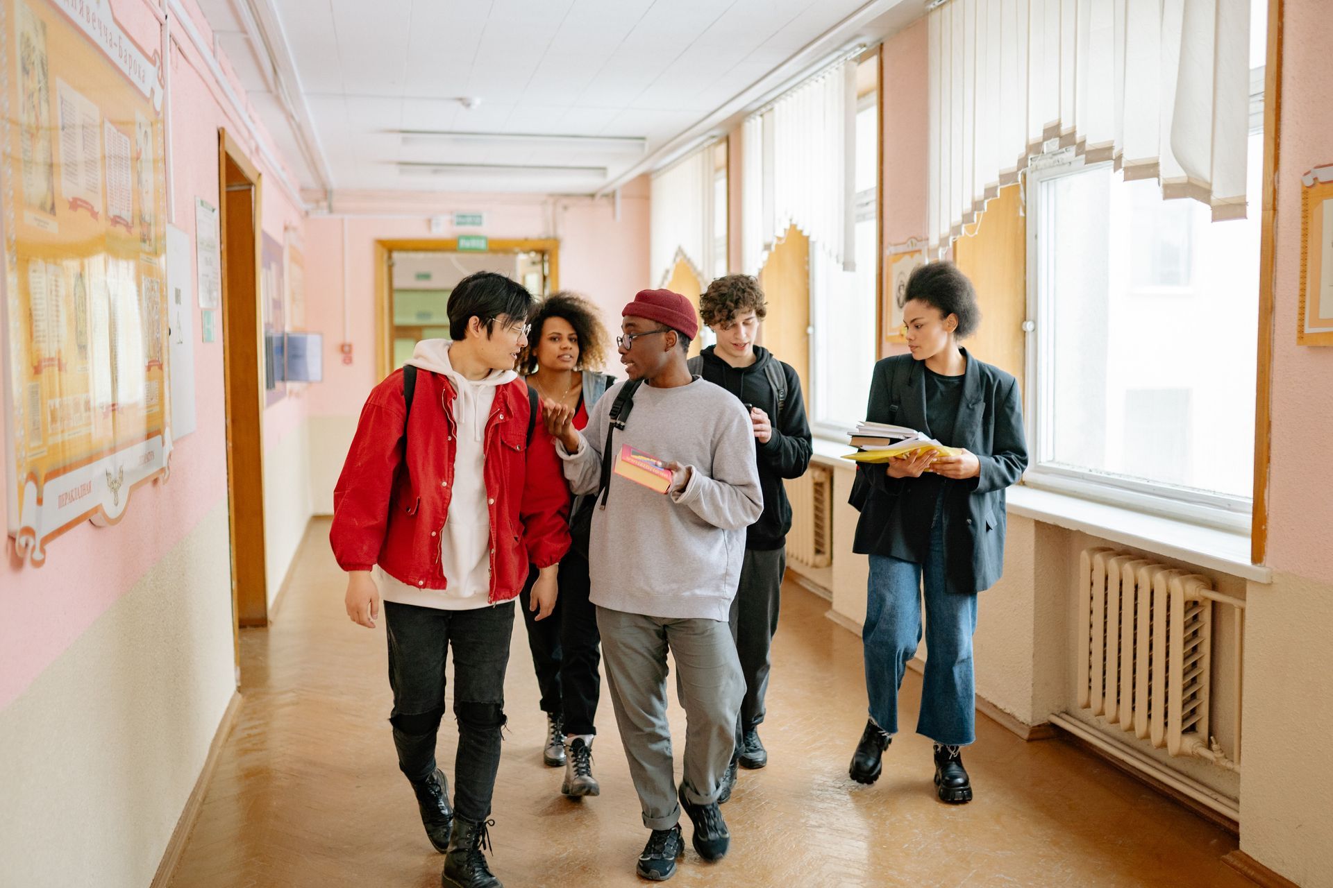 A group of young people are walking down a hallway.