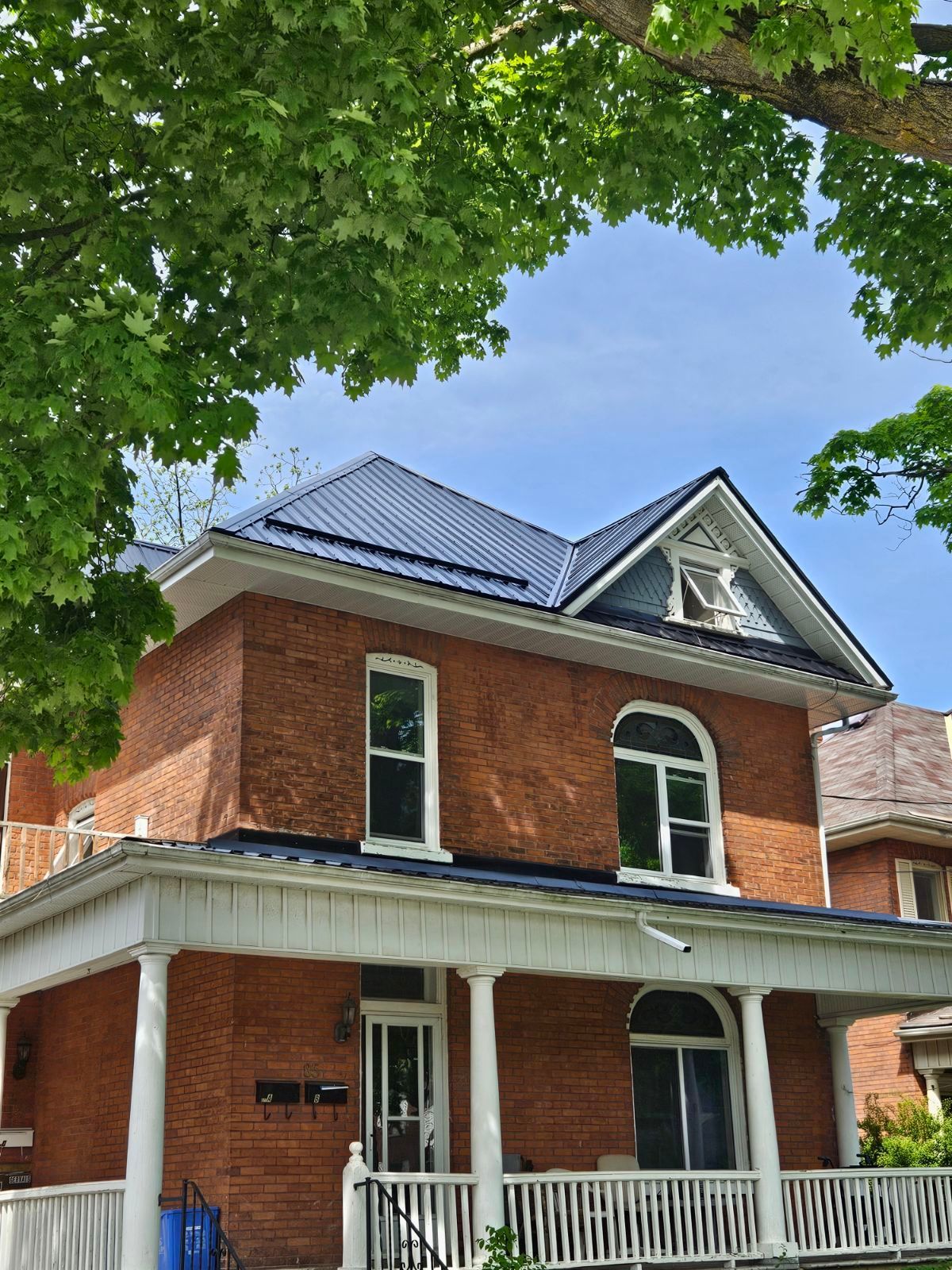 A brick house with a blue roof and a white porch.