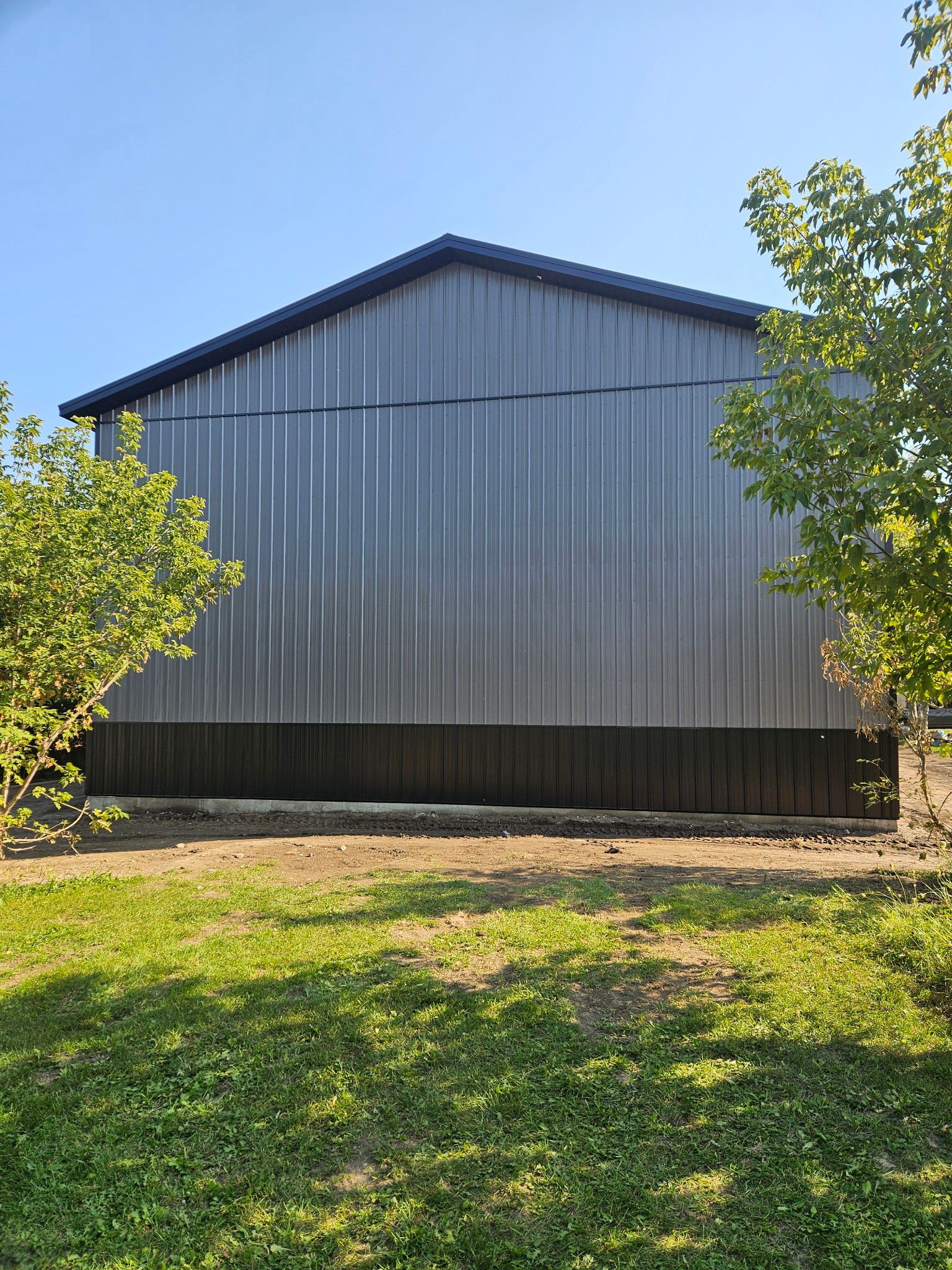 A large metal building is sitting in the middle of a grassy field.