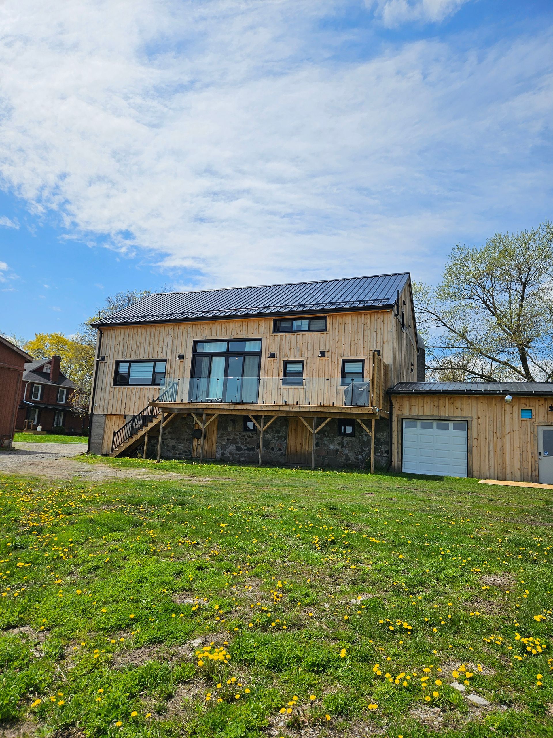 A large wooden house is sitting in the middle of a grassy field.