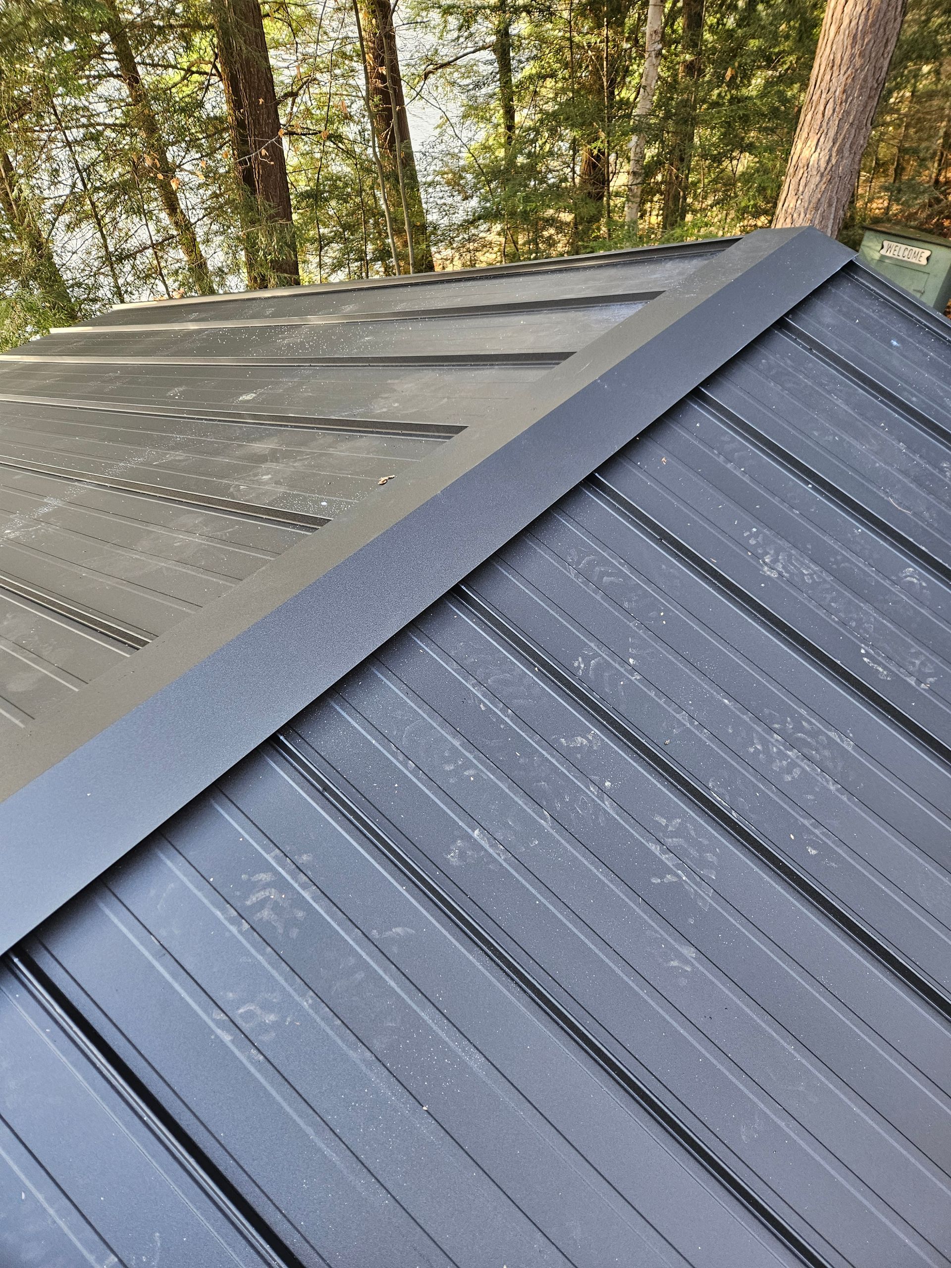A close up of a black roof with trees in the background