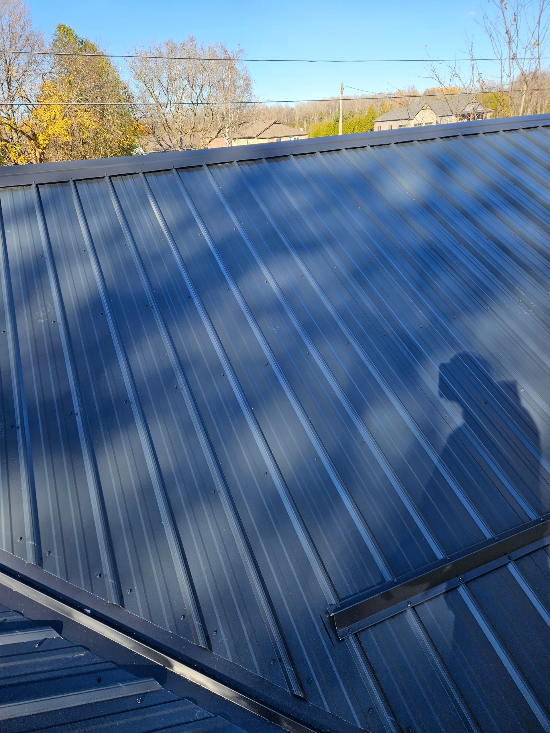 A black metal roof with a shadow of a person on it.