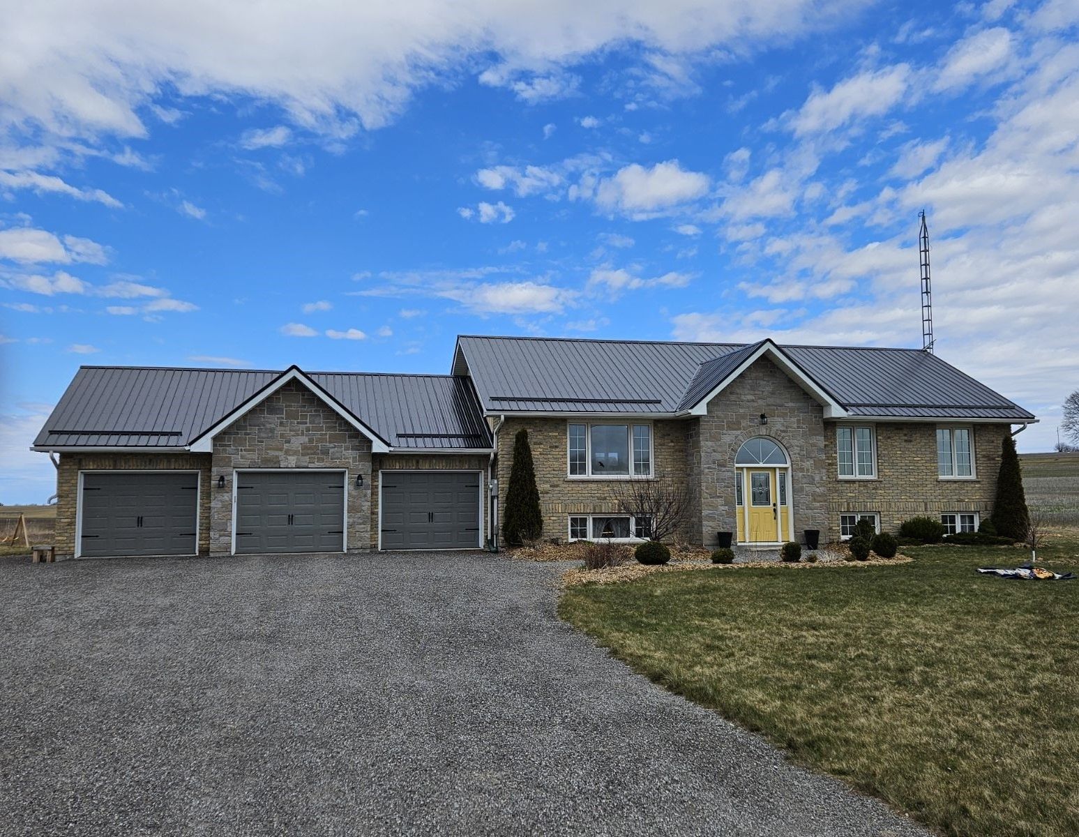 A large stone house with a gray roof and two garages