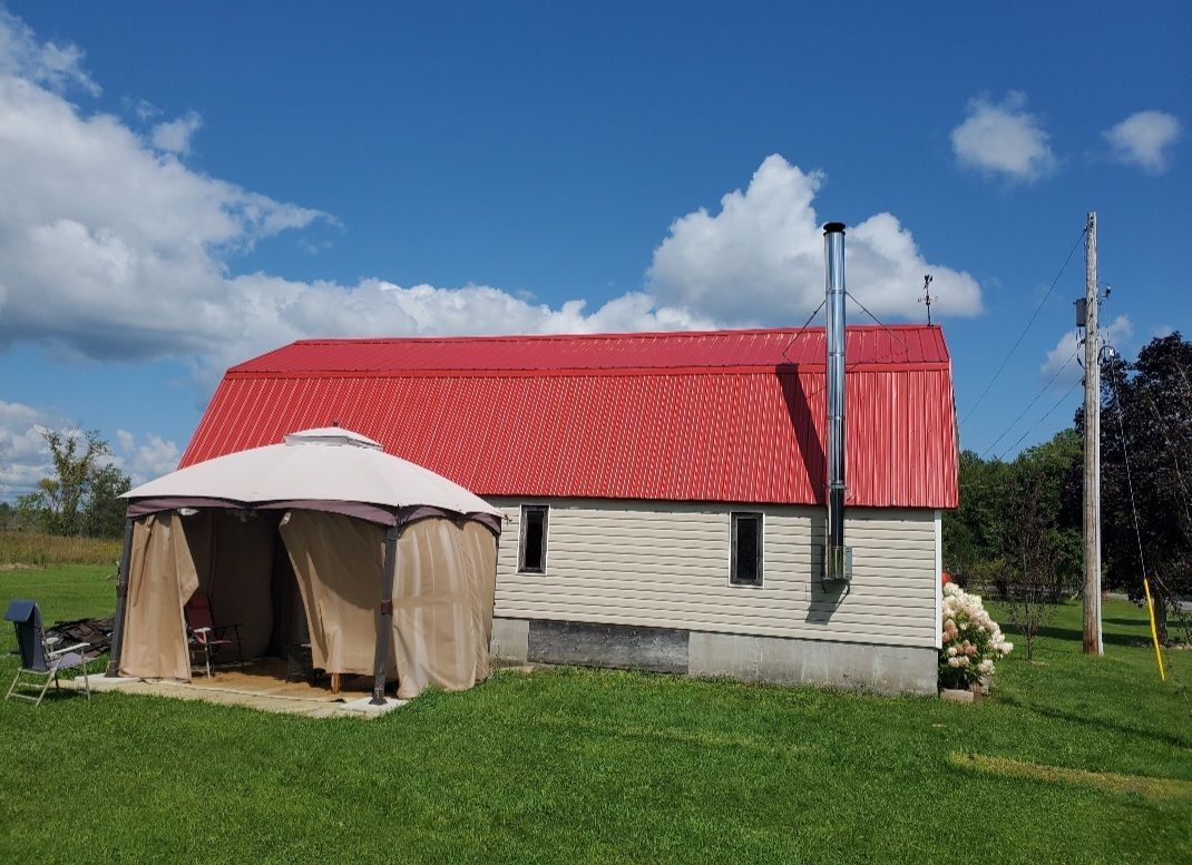 A white house with a red roof and a gazebo in front of it.