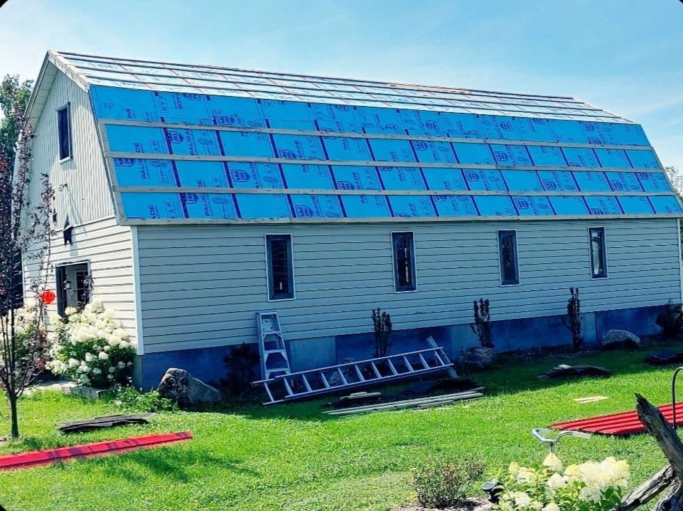 A white barn with a blue roof is being remodeled.
