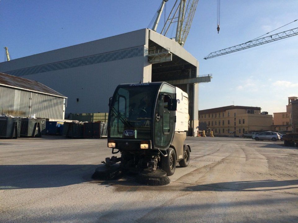 Uno spazzino sta pulendo un parcheggio di fronte a un edificio