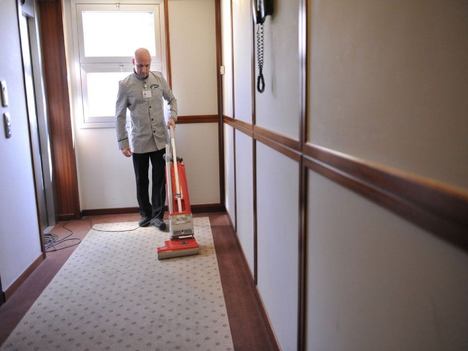 Un uomo sta usando un aspirapolvere per pulire un corridoio