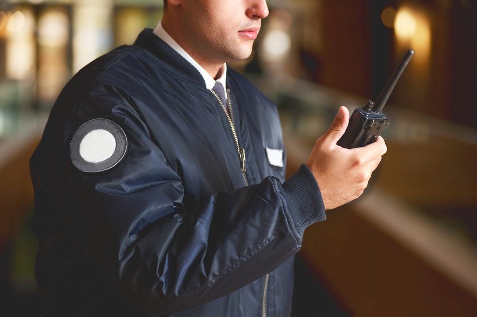 Una guardia giurata tiene in mano un walkie-talkie.