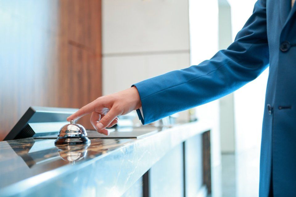 Una persona sta suonando il campanello alla reception di un hotel.