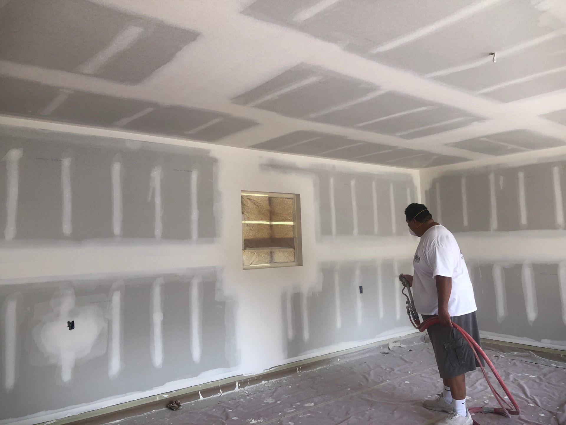 A man is spraying a room with a hose.