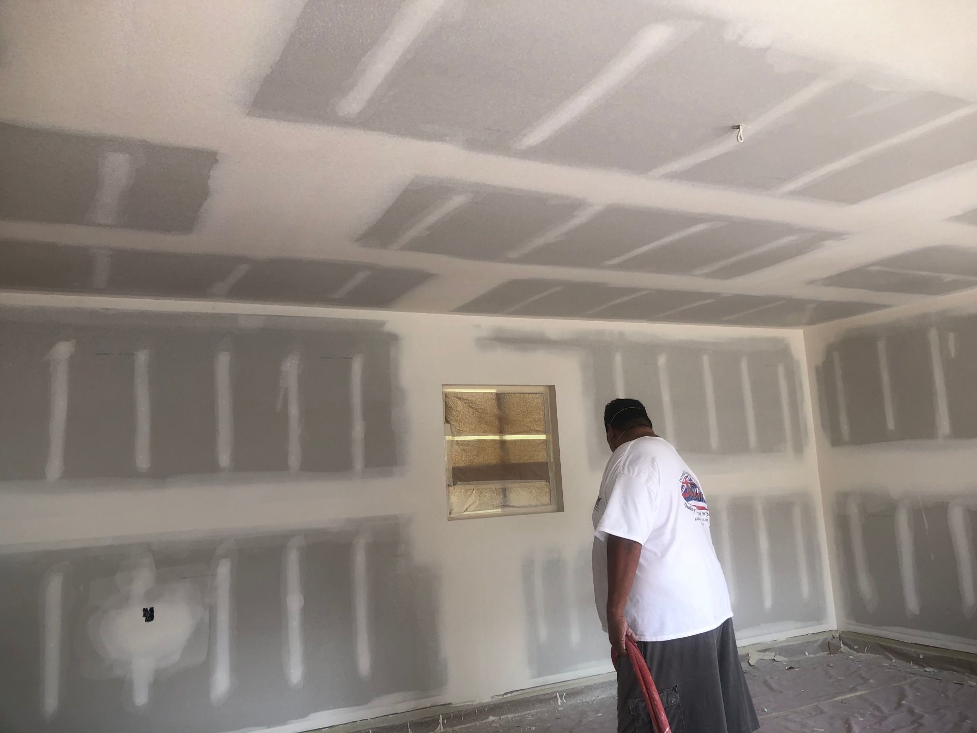 A man is painting the ceiling of a room with a broom.