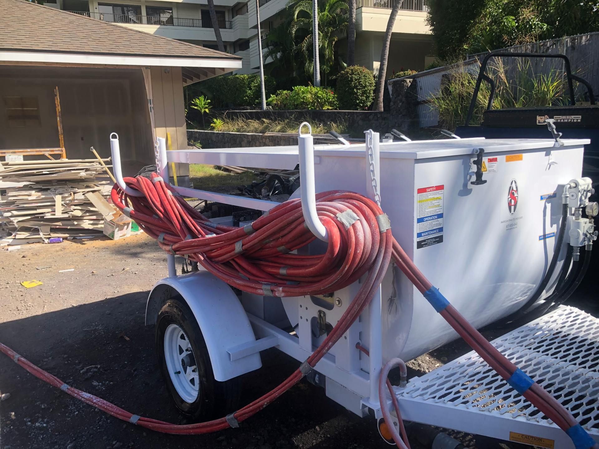A trailer with a hose attached to it is parked in front of a house