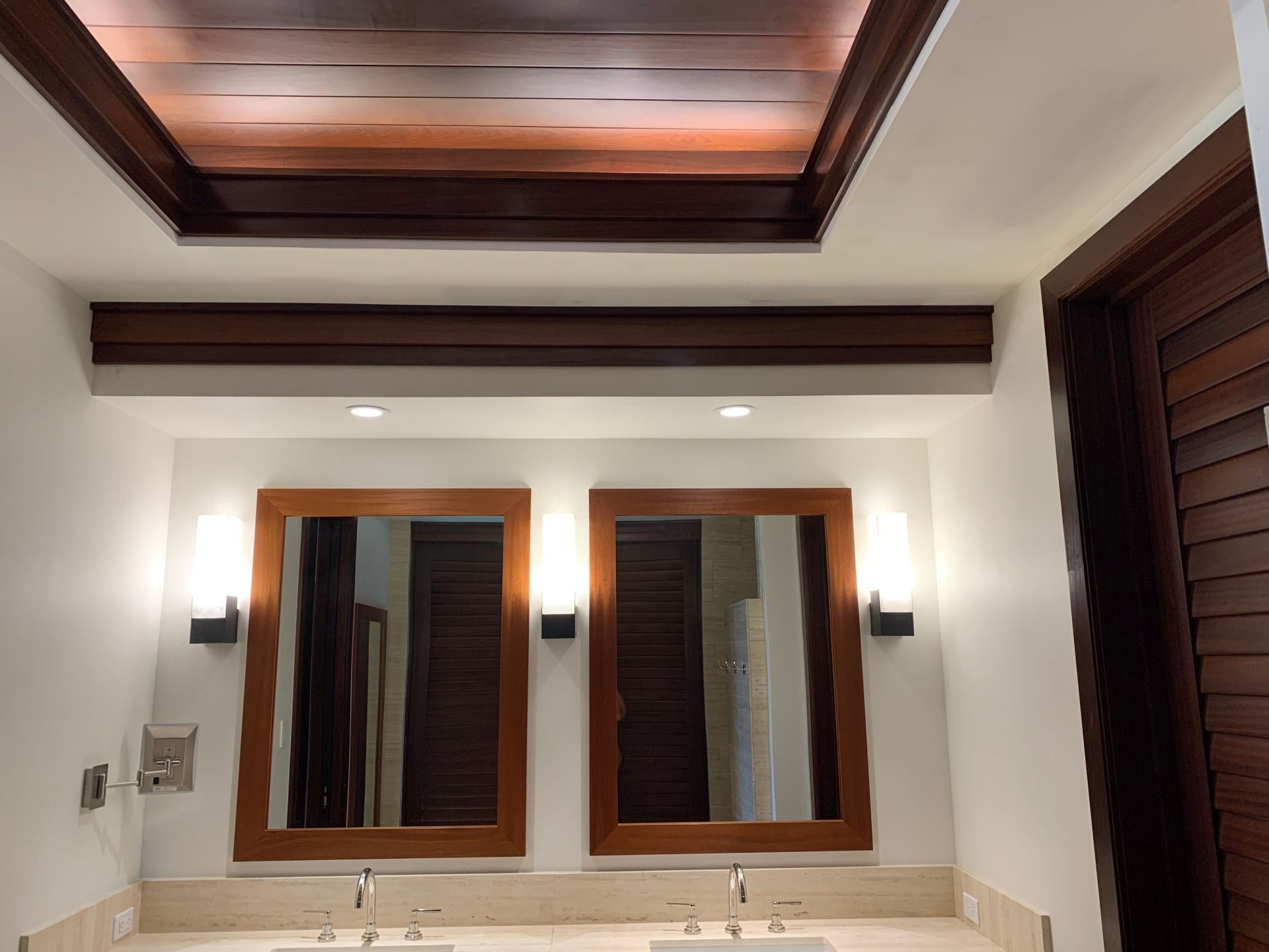 A bathroom with two sinks and two mirrors and drywall repair.