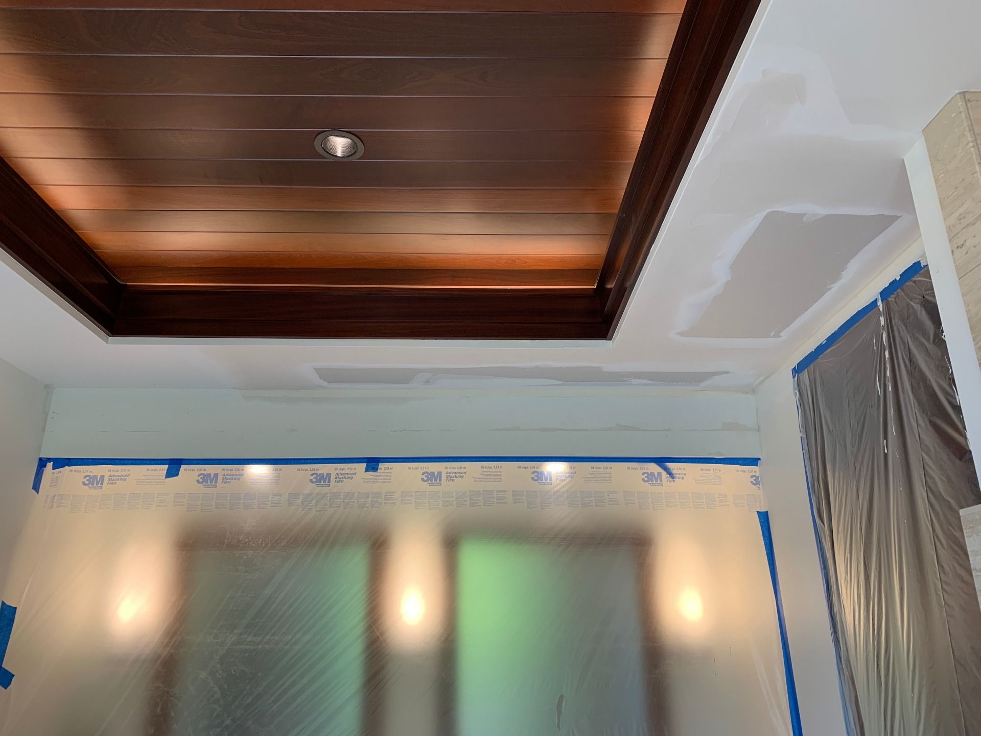 A room with a wooden ceiling and white walls and drywall repair. 