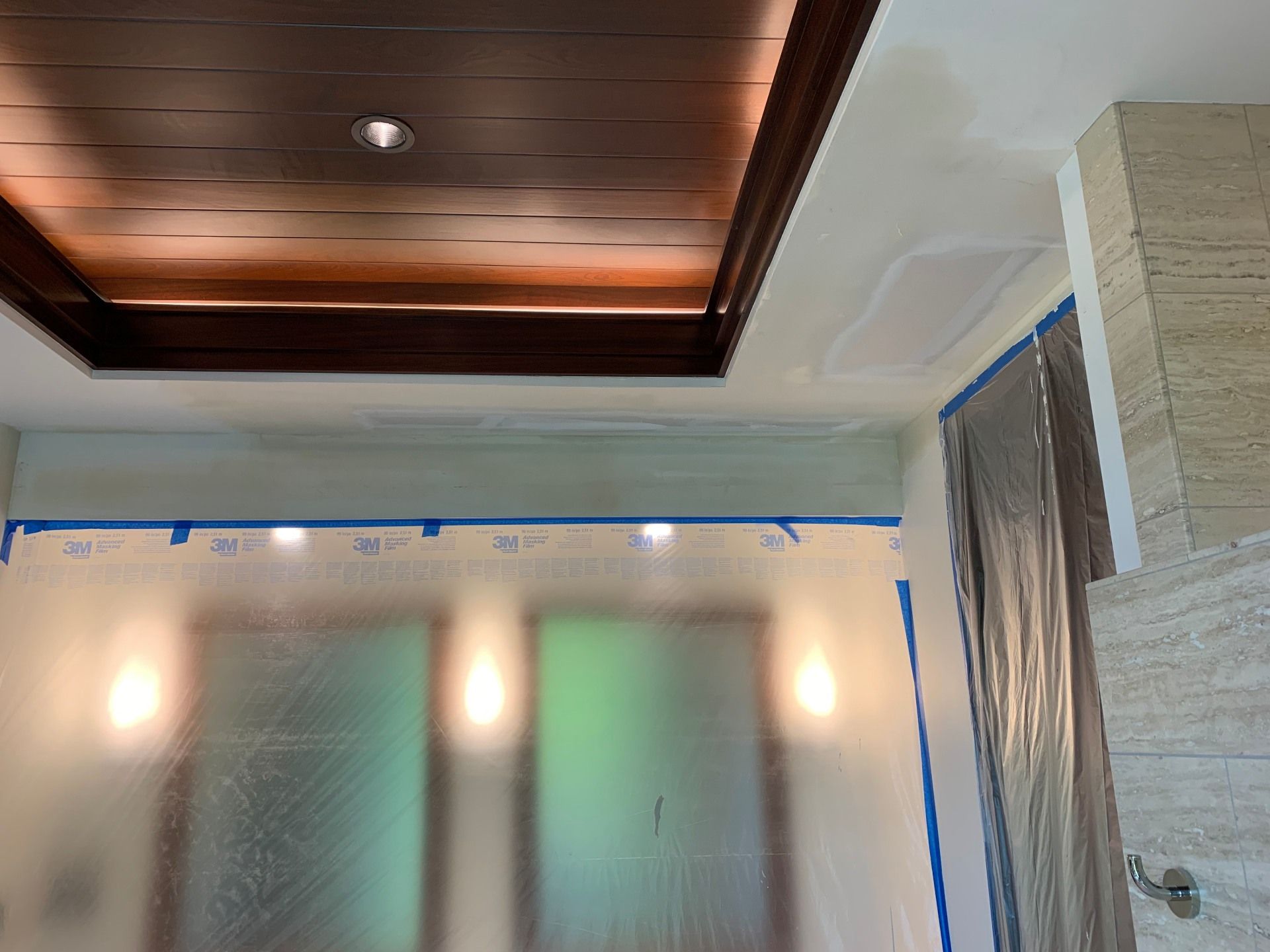 A room with a wooden ceiling and white walls is being painted.