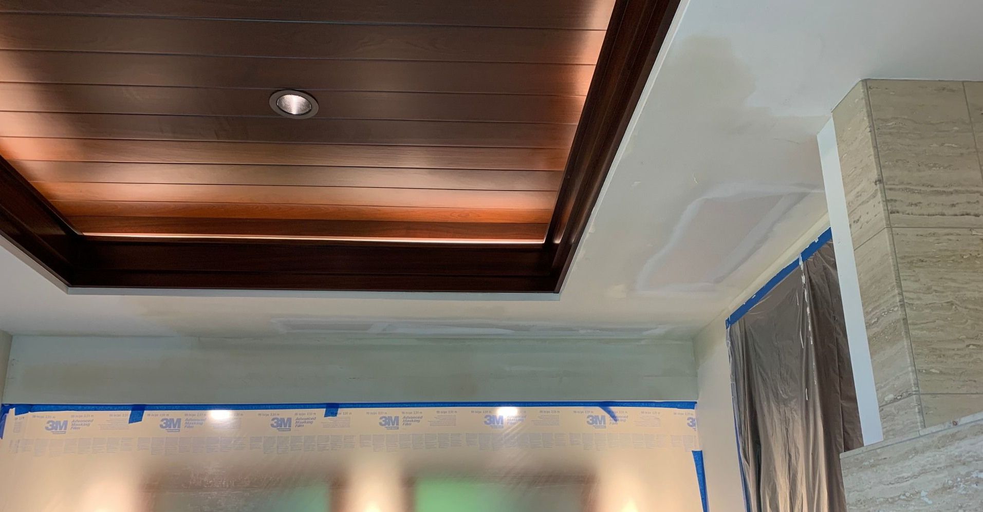 A room with a wooden ceiling and a white wall showing drywall repair.