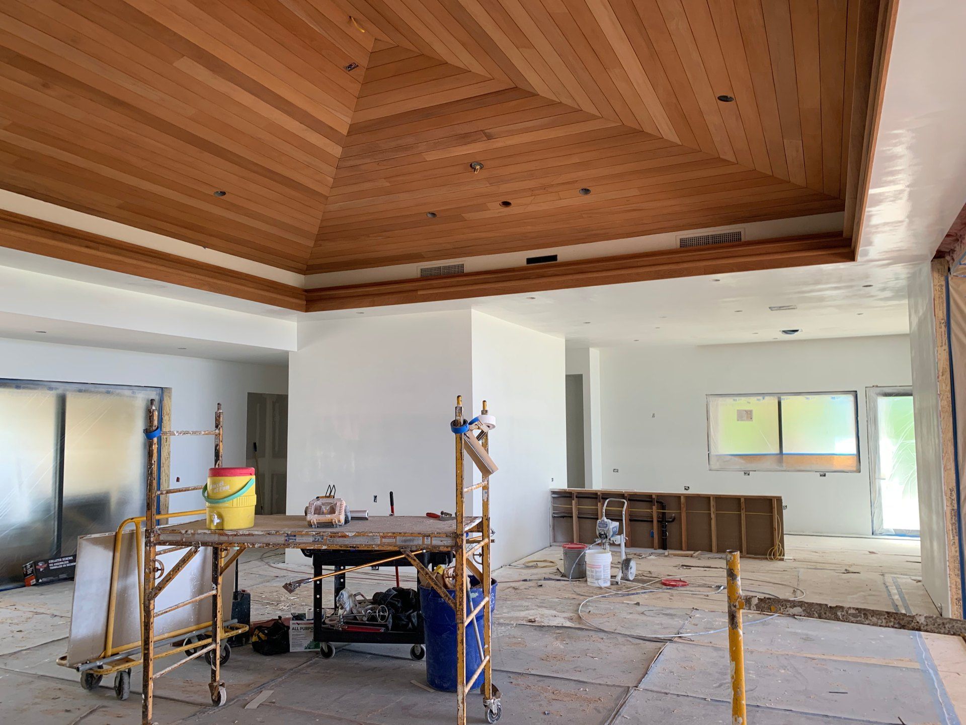 A large room with a wooden ceiling and scaffolding and drywall.